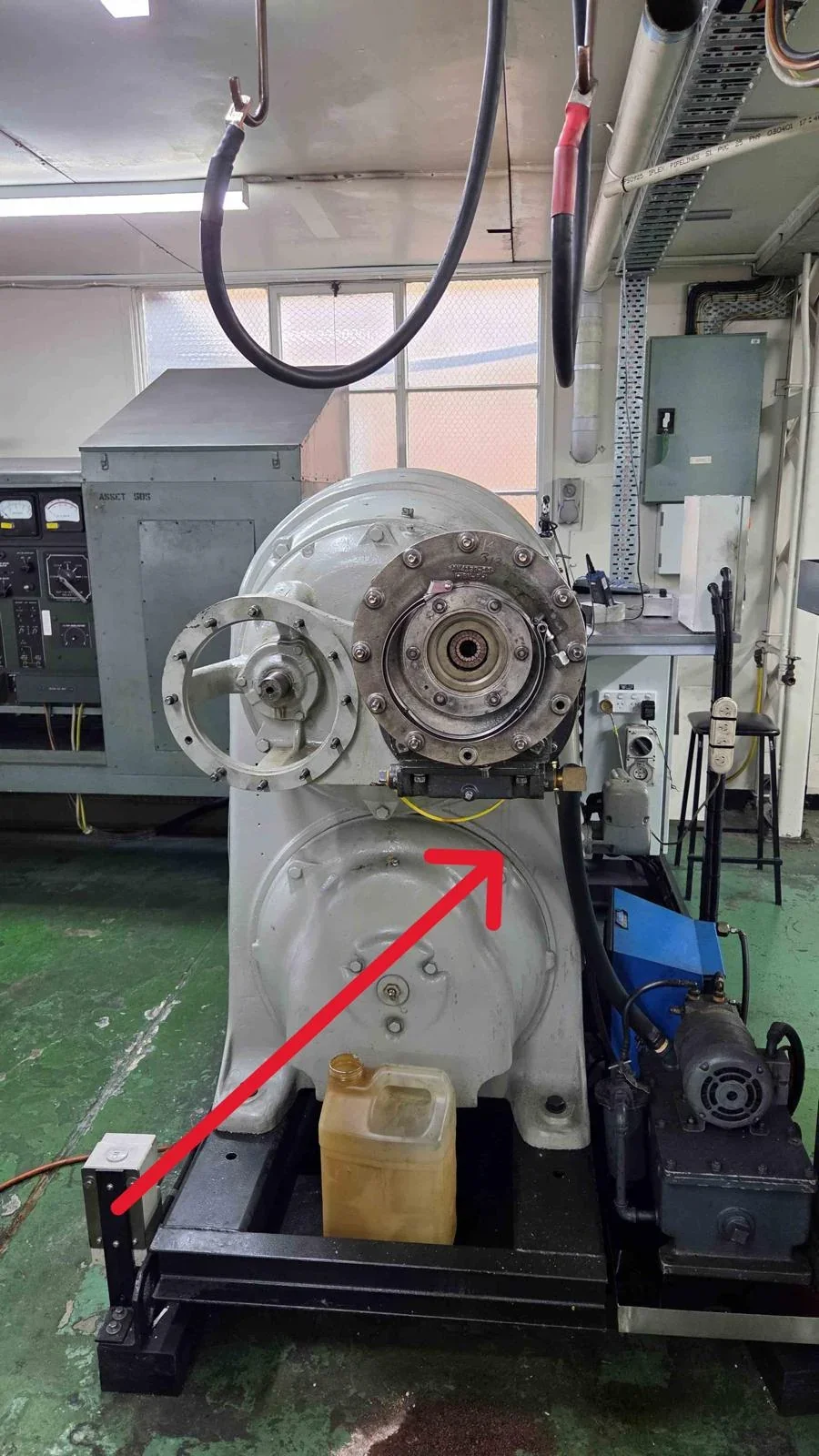 Heavy grey industrial machine with a circular flanged assembly marked for relocation