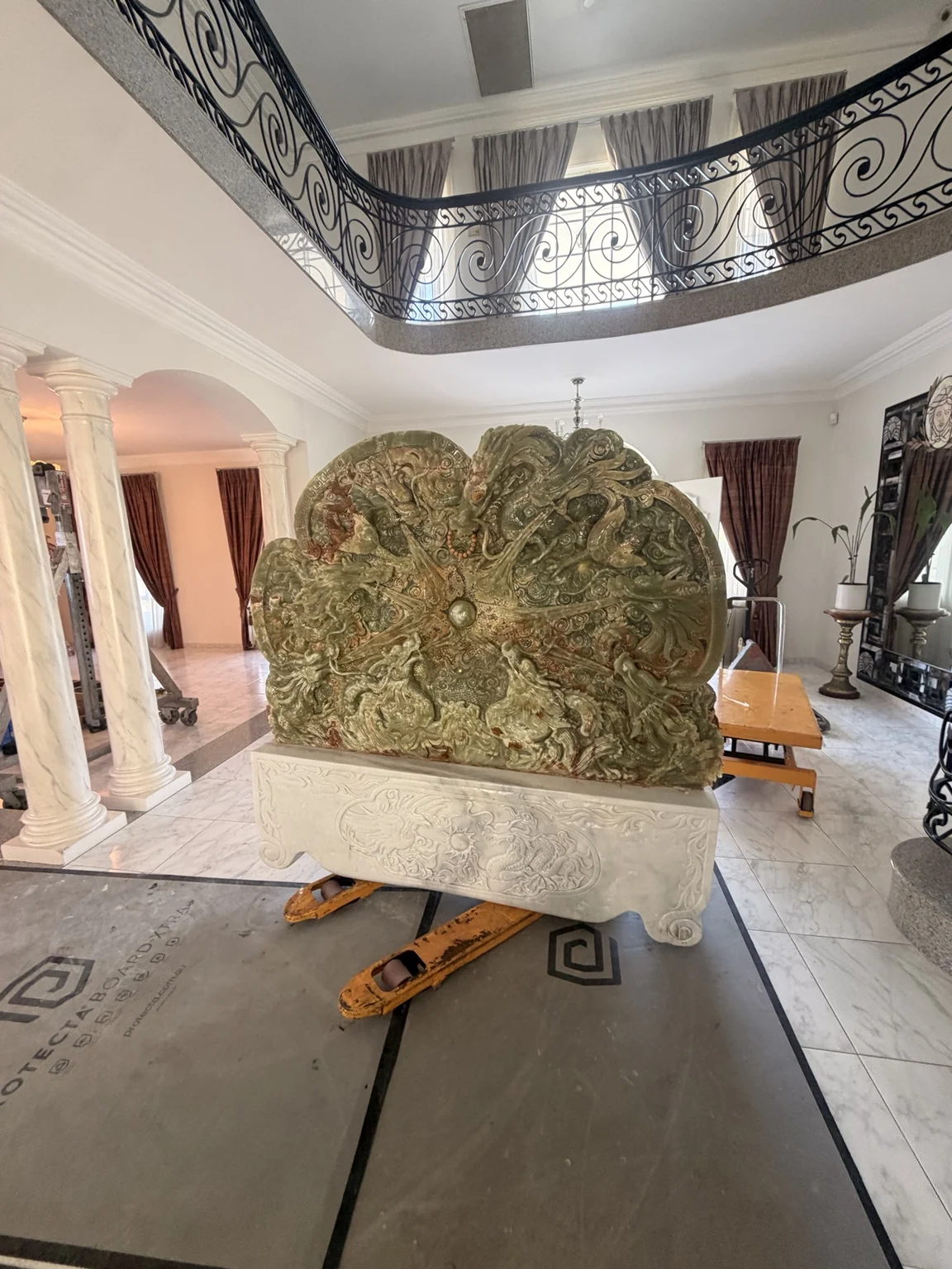Carved stone panel and white decorative base positioned above pallet jacks