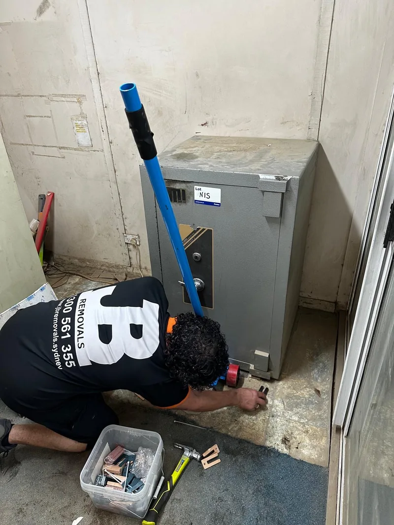 JB Removals team member working with moving equipment beside the safe in a confined entry