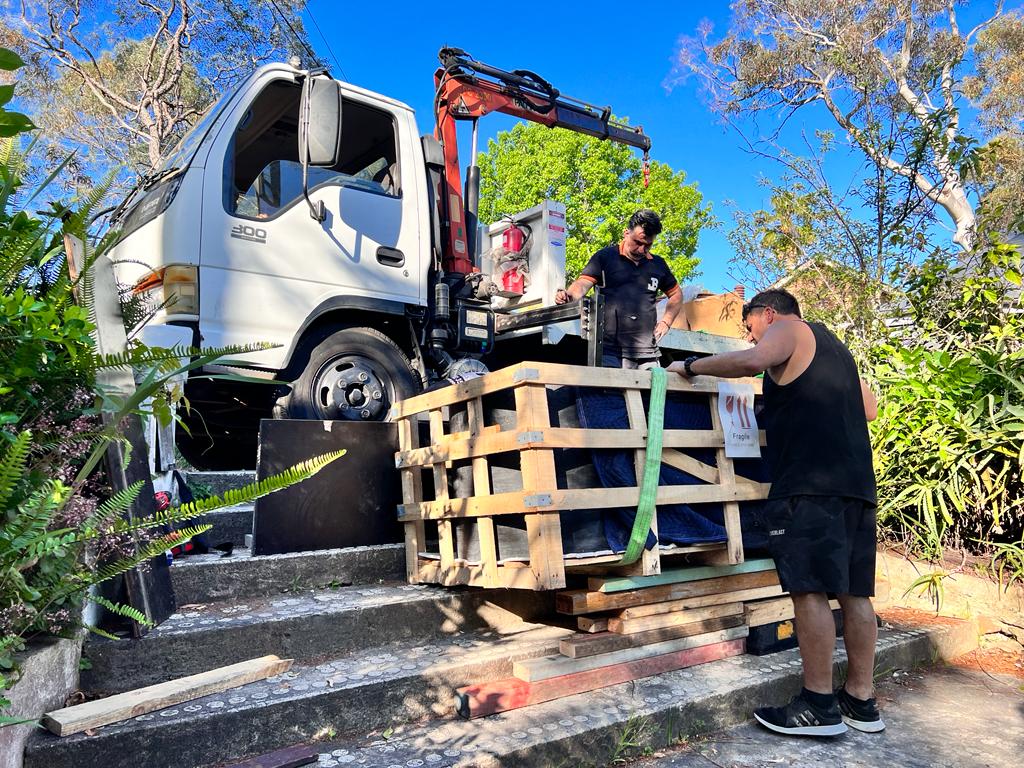JB crew guiding a protected load beside a crane-equipped truck