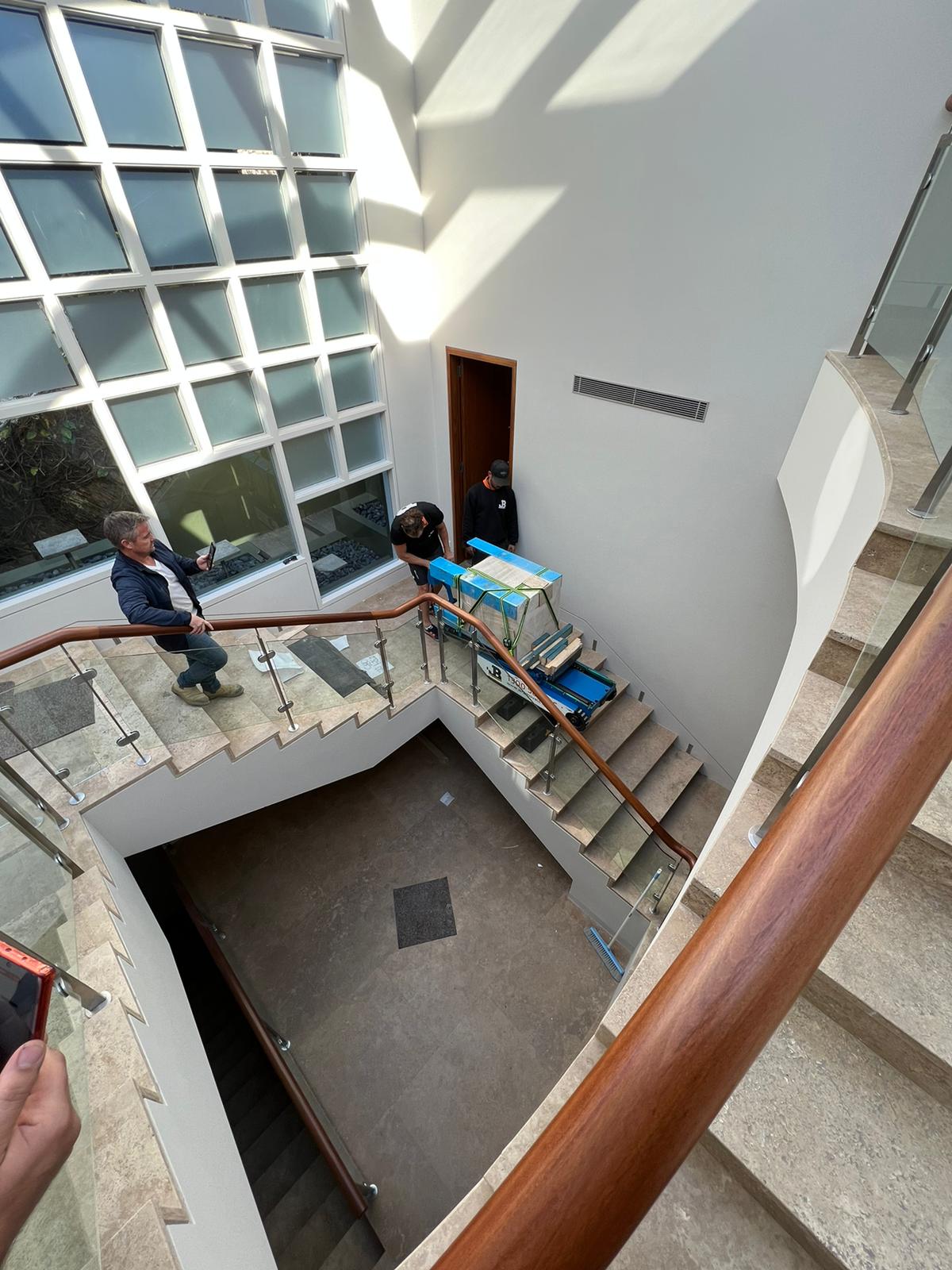JB Removals crew preparing a heavy strapped item on a stair-climbing machine inside a Sydney home