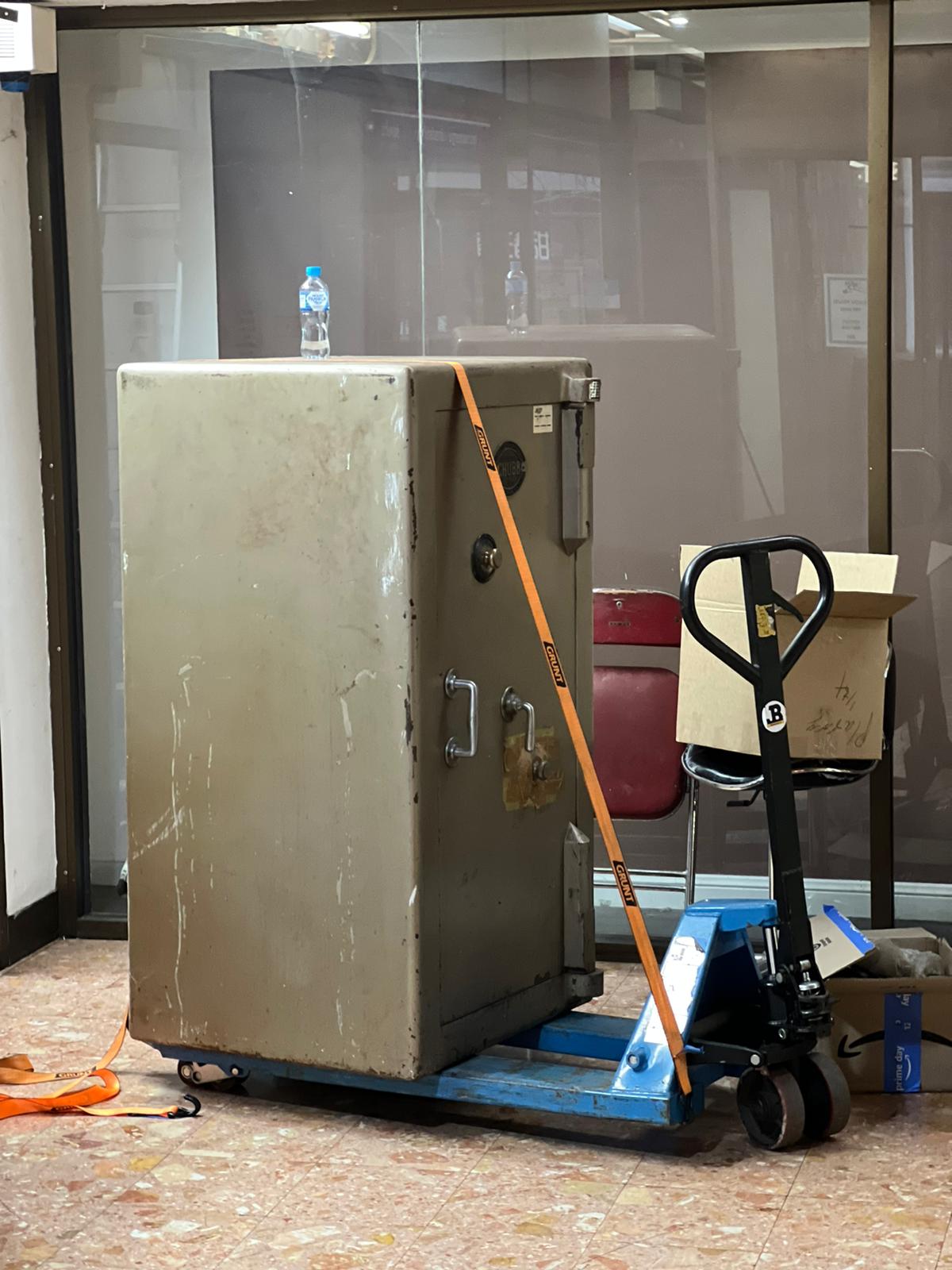 Heavy safe secured with a lifting strap on a pallet jack before transport